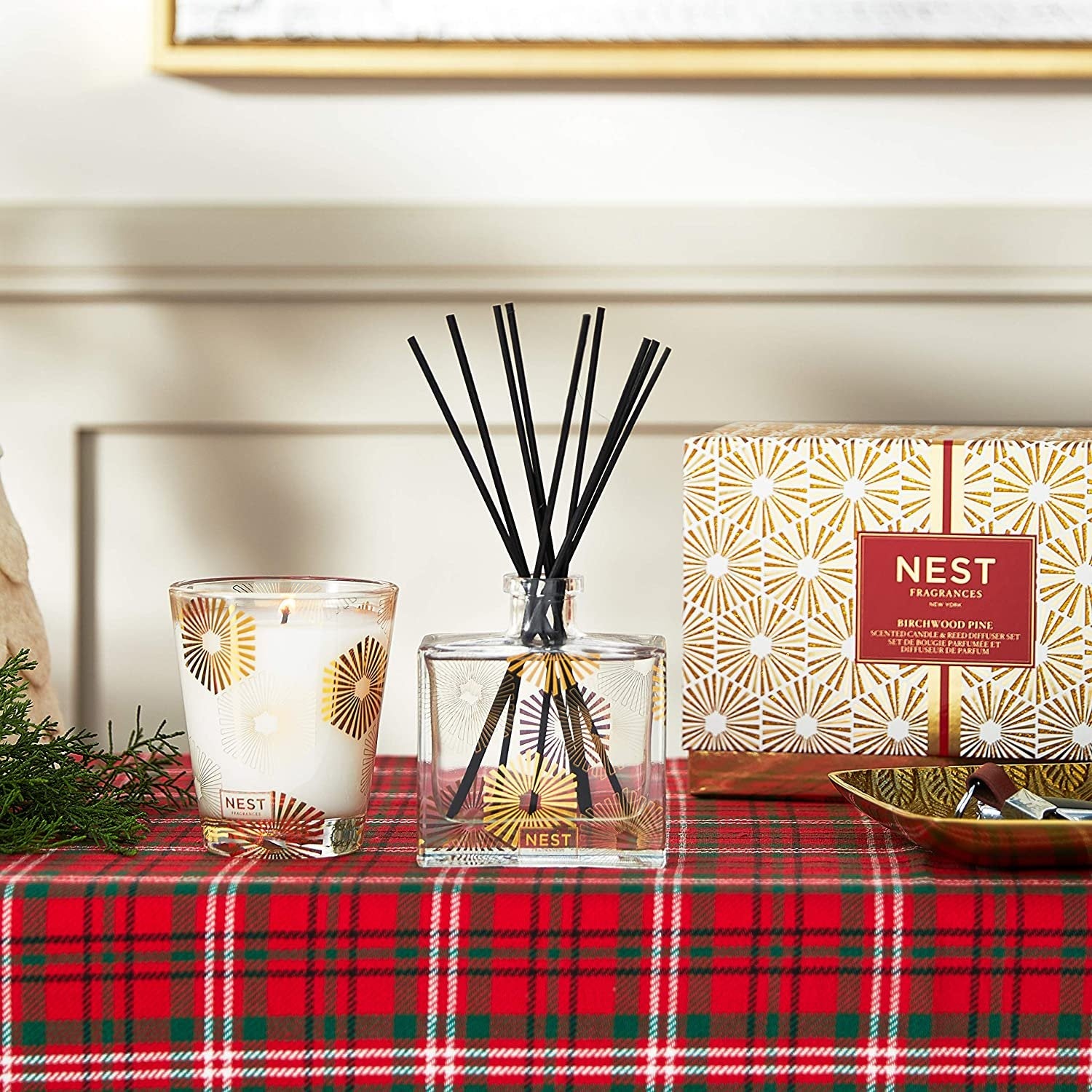 NEST New York Birchwood Pine Classic Candle & Reed Diffuser Set emitting warm, cozy woodsy fragrance for a festive home ambiance.